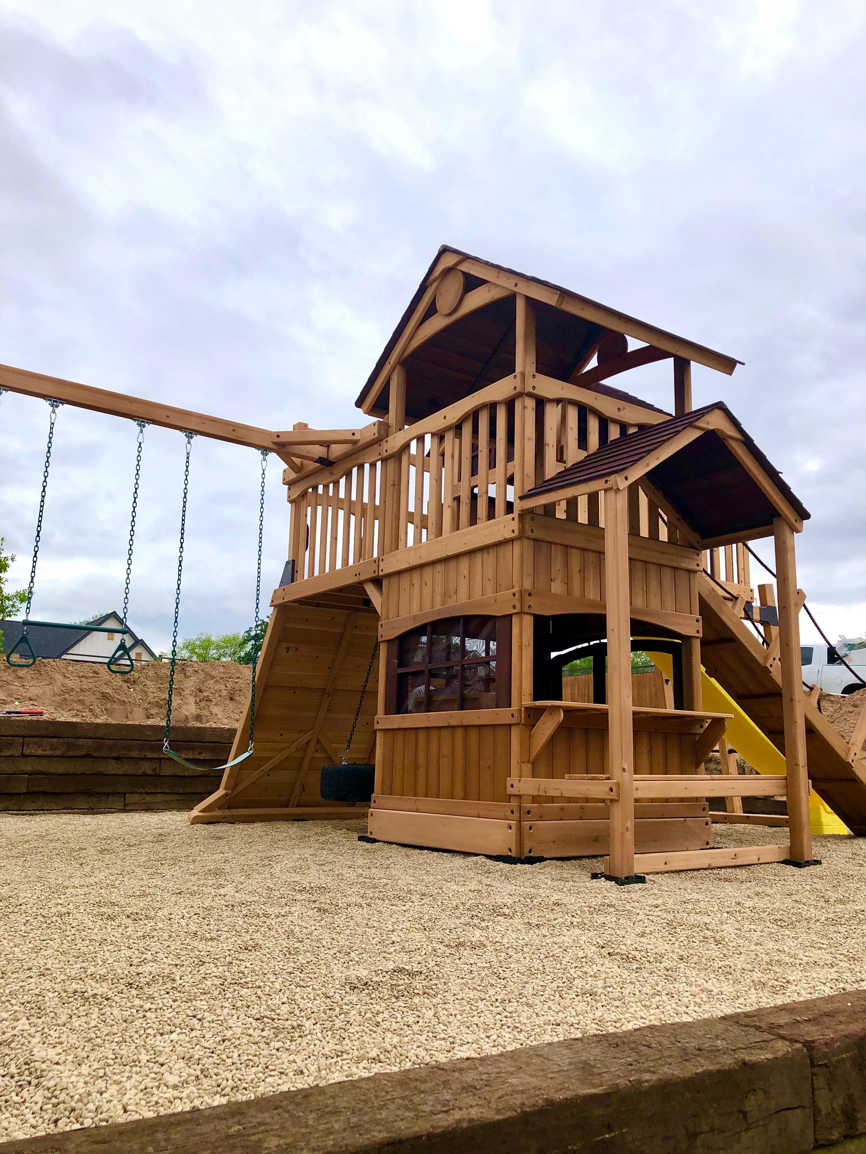 Compact wooden swing set in a finished backyard play area