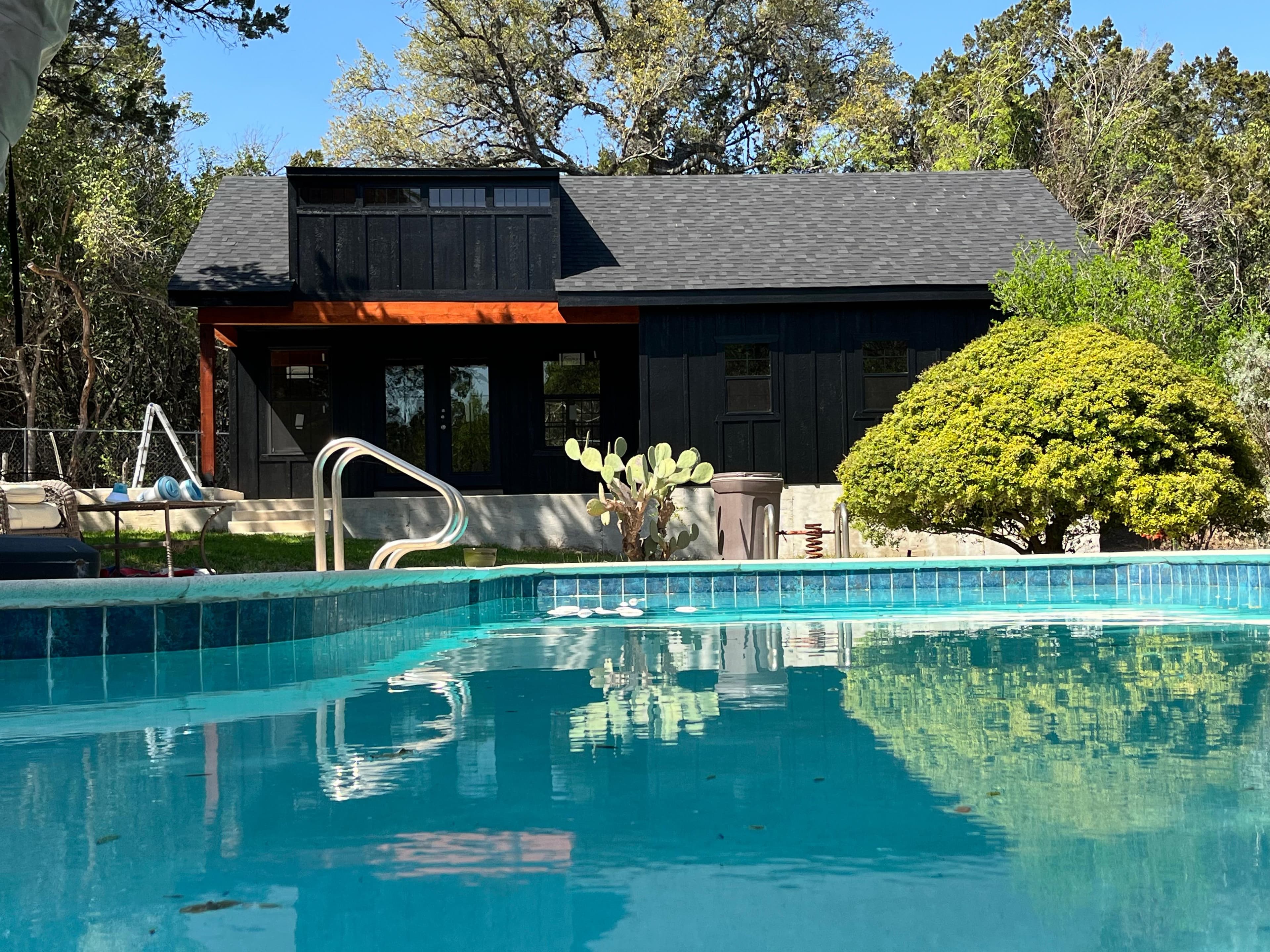 Modern black shed and backyard building beside a pool